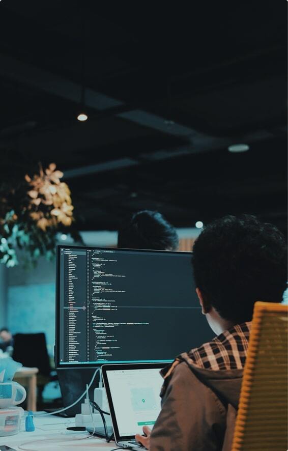 Man in the office looking at monitor with code.